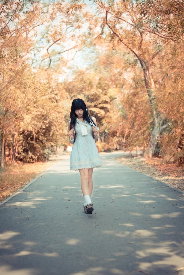A cute Asian Thai girl is walking on a forest path alone in soft