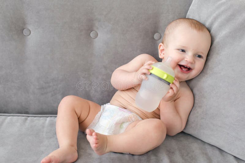Cheerful baby with bottle on sofa royalty free stock photos Cheerful baby with bottle on sofa royalty free stock photos