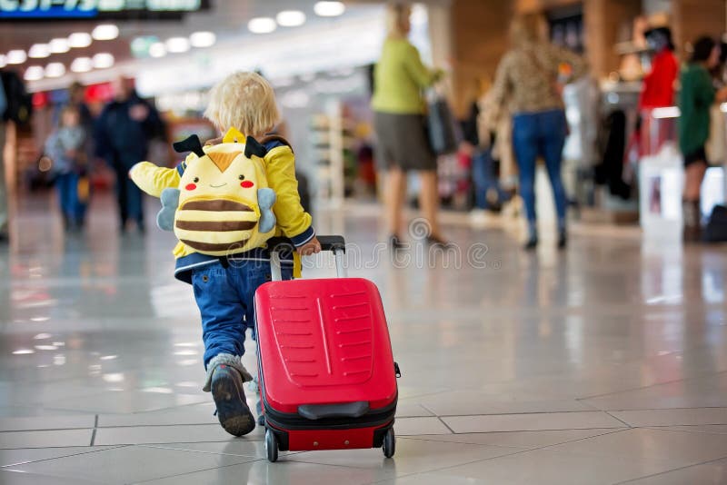 Cute  baby boy, running late for boarding to flight in airport transit hall near departure gate. Active family lifestyle travel by
