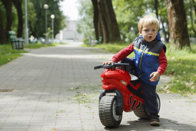 Cute Baby Boy Sitting On A toy Motorcycle in the park. copy space