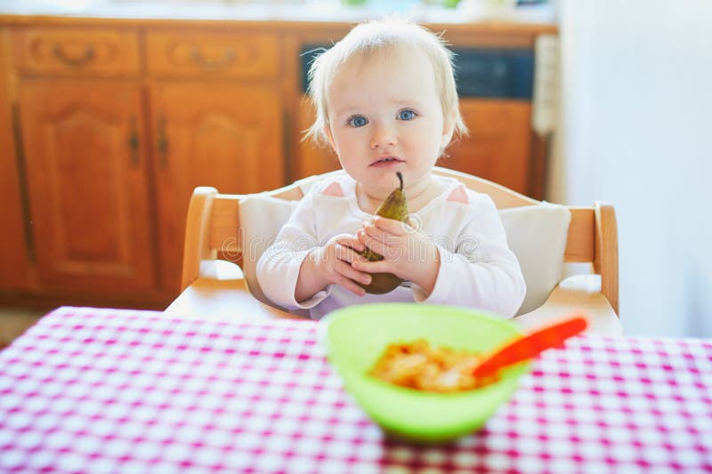 Cute Baby Girl Eating Pear in the Kitchen Stock Image - Image of pear ...