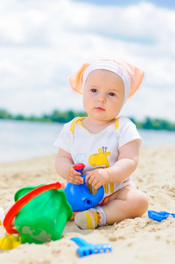 Cute baby girl playing on the beach with sand.