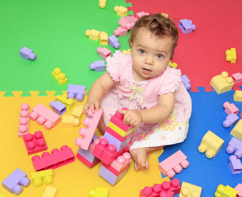 Cute baby girl plays with multicolored blocks toy