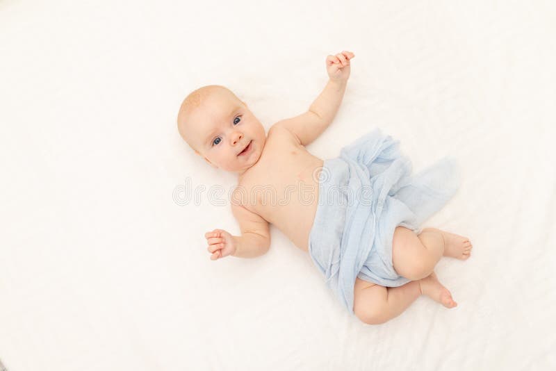 A baby is lying on a white background. Bedding for children. 6 months. Healthy baby in the crib. Space for text