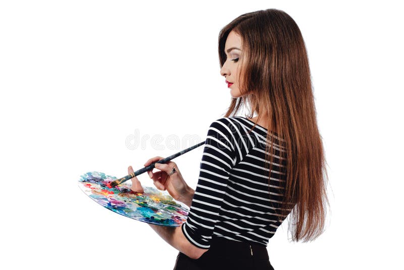 Cute beautiful girl artist holding a palette and brush in the process draws inspiration. White background, isolated. royalty free stock photography Cute beautiful girl artist holding a palette and brush in the process draws inspiration. White background, isolated. royalty free stock photography