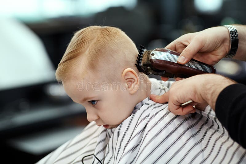 Cute Blond Baby Boy with Blue Eyes in a Barber Shop Having Haircut by  Hairdresser. Hands of Stylist with Tools Stock Image - Image of blue,  haircut: 145291885