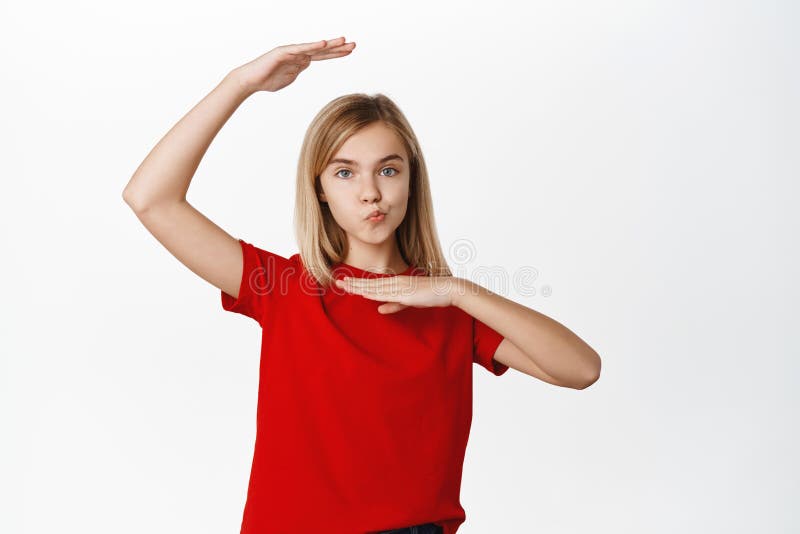 Cute blond little girl posing against white background, showing her beautiful face, glamour photo, standing in tshirt