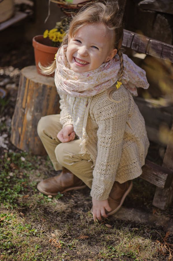 Cute blonde child girl having fun in early spring garden