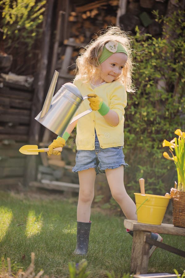 Cute blonde child girl having fun playing little gardener