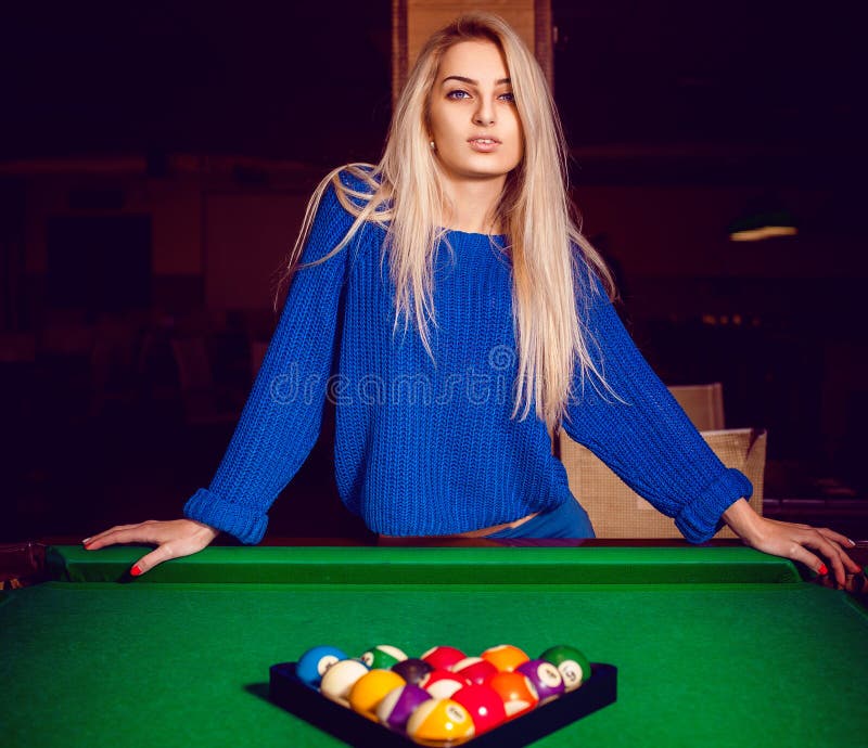 Cute blonde posing near a billiard table with a pyramid of balls