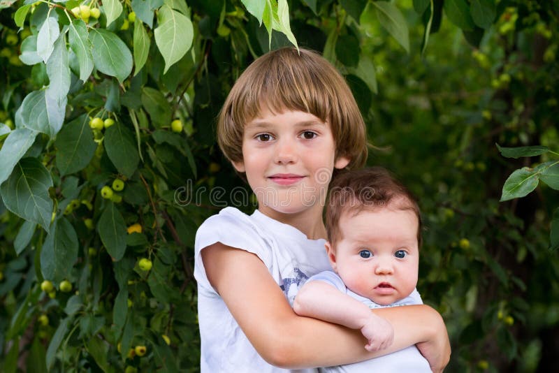 Cute boy holding his baby sister outside in a park stock photography Cute boy holding his baby sister outside in a park stock photography