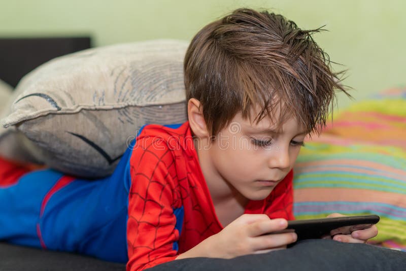 Cute Boy Holding Mobile Phone. Feeling Bored in Home Isolation. Stock