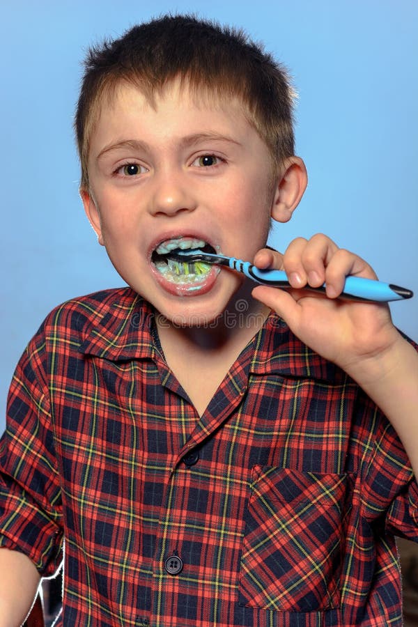 A Cute Boy in a Pajamas Brushes Teeth with Toothpaste before Bedtime on