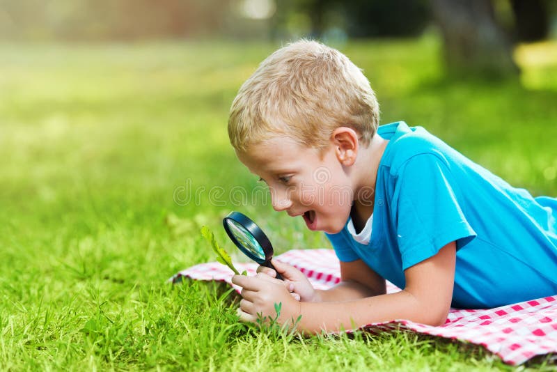 Cute boy in a park with a magnifying glass