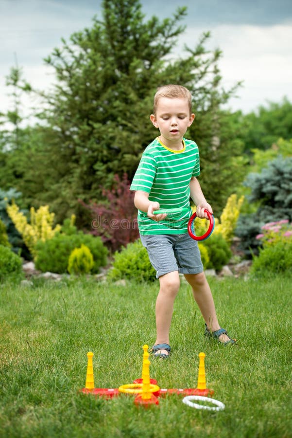Cute Boy Playing a Game Throwing Rings Outdoors in Summer Park Stock