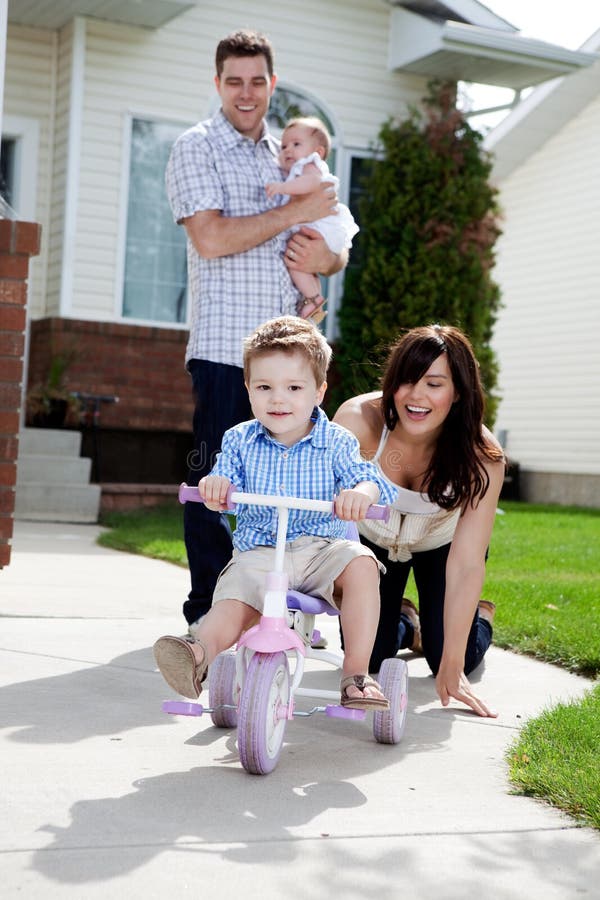 Young happy boy riding tricycle with family watching. Young happy boy riding tricycle with family watching