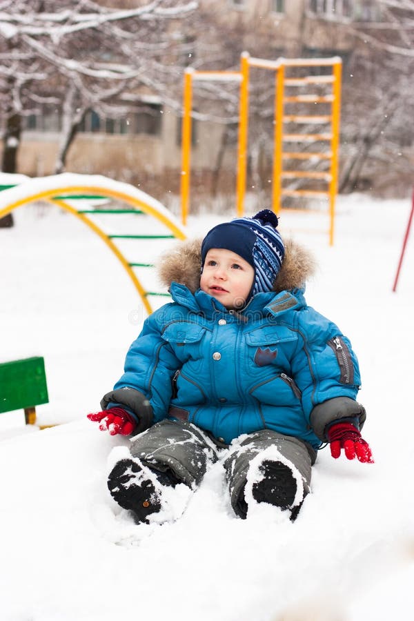 Cute boy sitting in snow outdoor