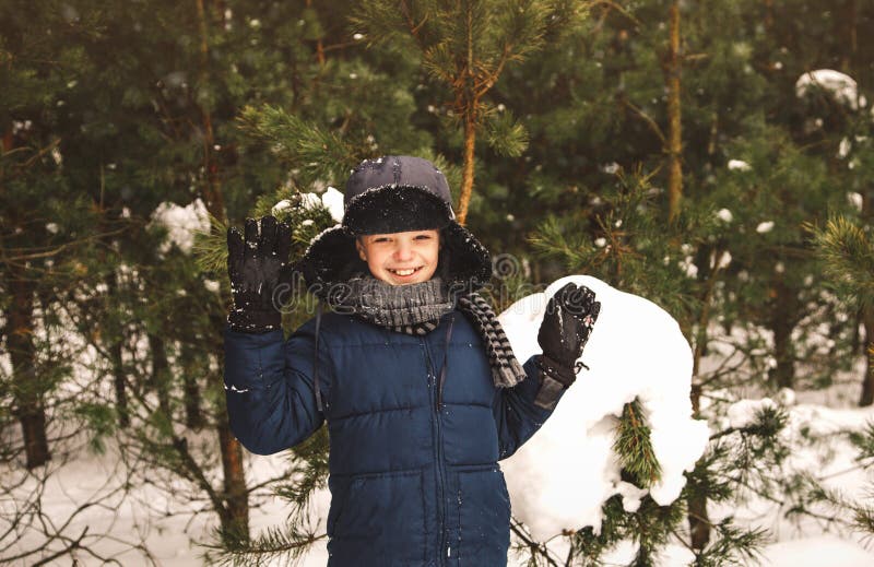 Cute boy smiles and waves his hands in a beautiful snowy forest in winter