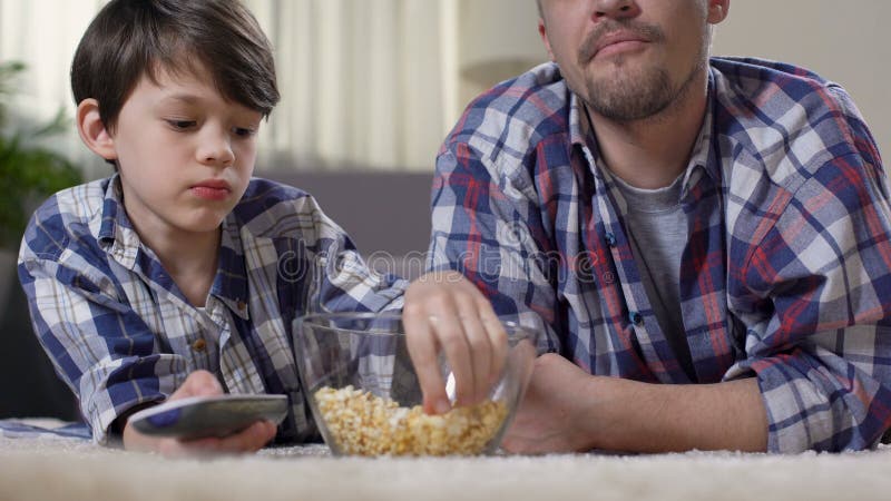 Cute boy watching movie with dad, enjoying time with his father, family love