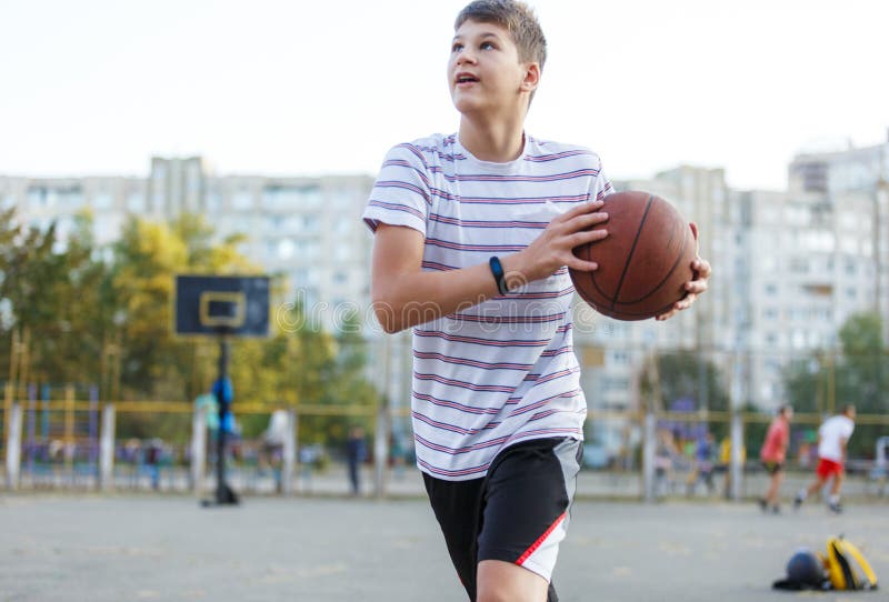 Cute Boy In White T Shirt Plays Basketball On Street Playground