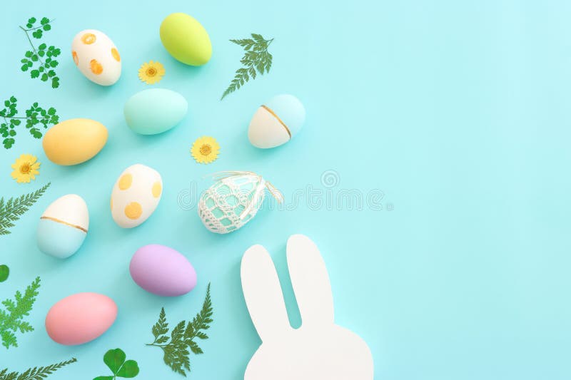 Cute Bunny Next To Easter Colorful Eggs Over Blue Pastel Background