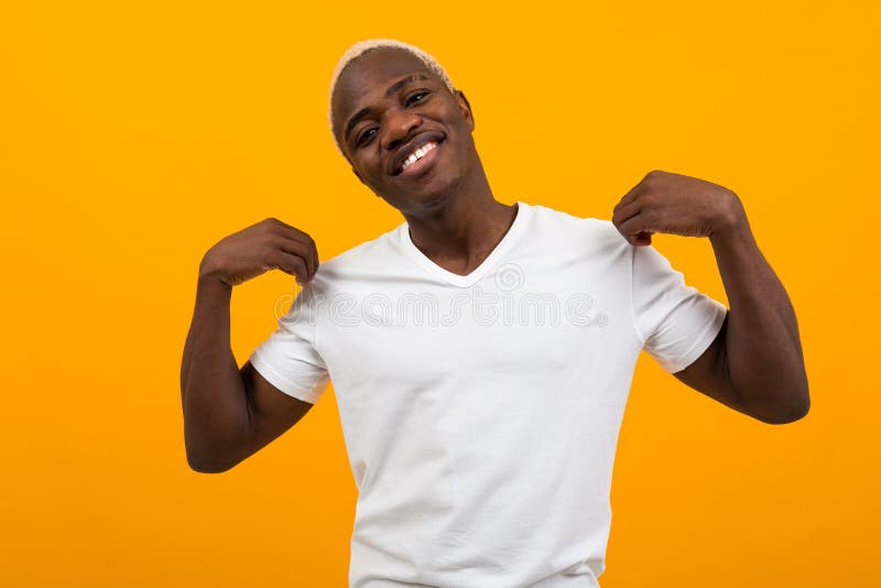 Cute charming handsome black blond american man in white t-shirt with mockup on yellow background