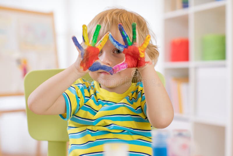 Cute cheerful kid with hands painted in bright colors