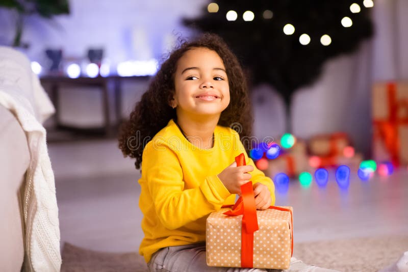 Cute cheerful little afro girl opening Christmas gift royalty free stock photo Cute cheerful little afro girl opening Christmas gift royalty free stock photo