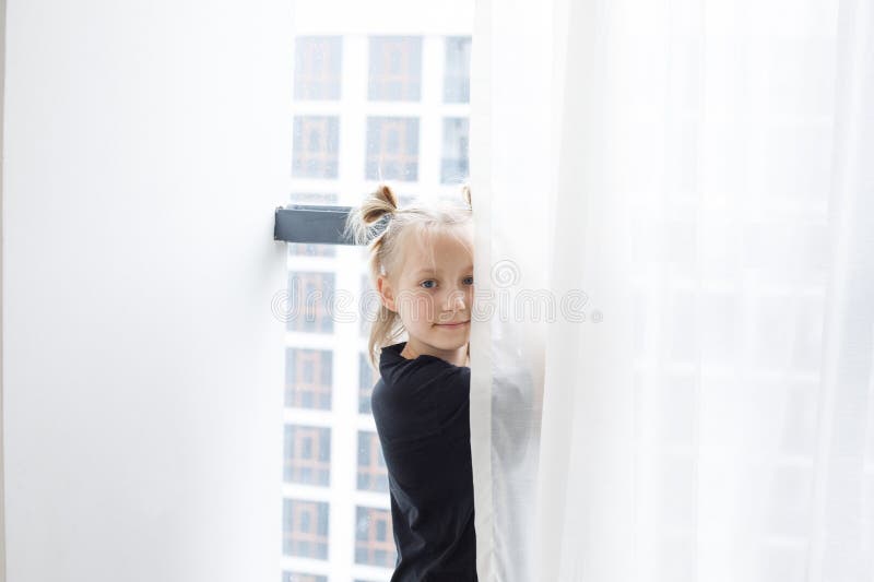 Cute child girl standing at the window at home royalty free stock photos