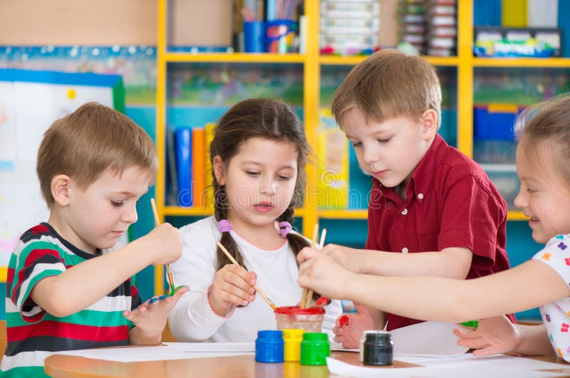 Cute children drawing with colorful paints at kindergarten stock image