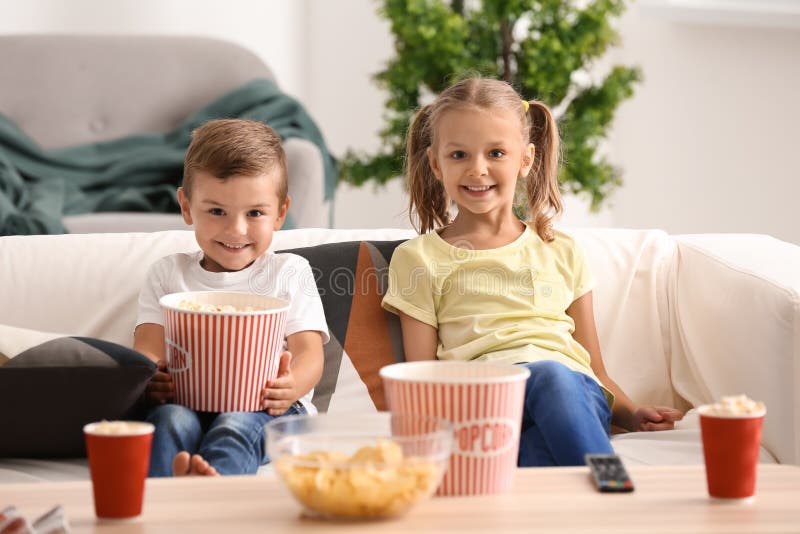Cute Children Eating Popcorn while Watching TV at Home Stock Image