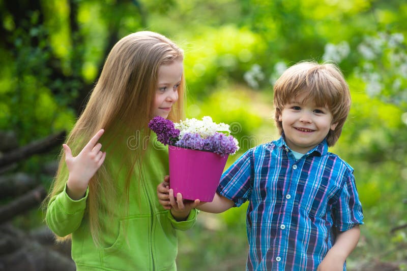 Cute children gardening and planting flowers to the ground in spring garden, seasonal outdoor activities, happy