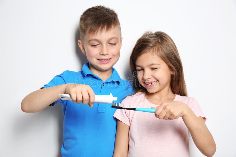 Cute children with toothbrush and paste on white