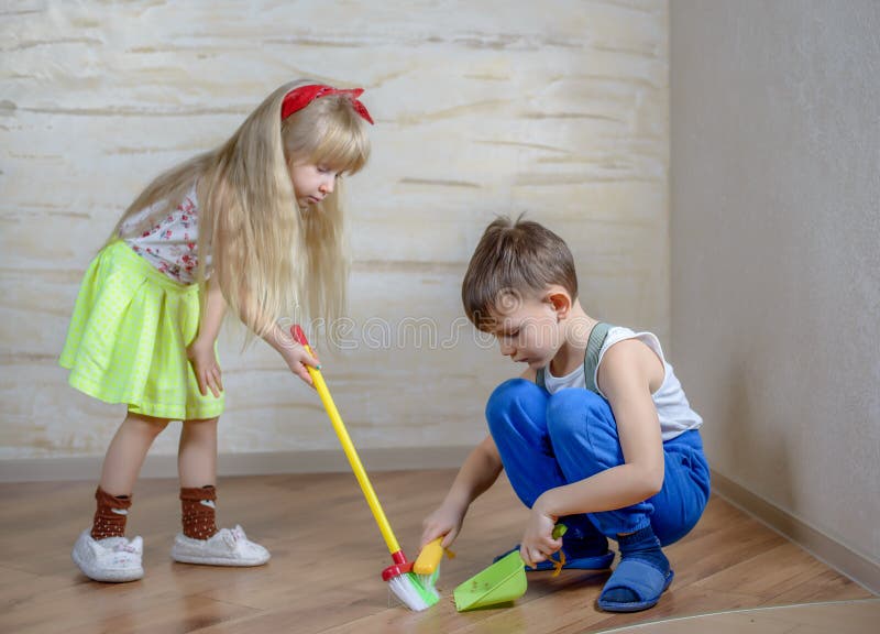 Cute children using toy broom and dustpan royalty free stock photography Cute children using toy broom and dustpan royalty free stock photography