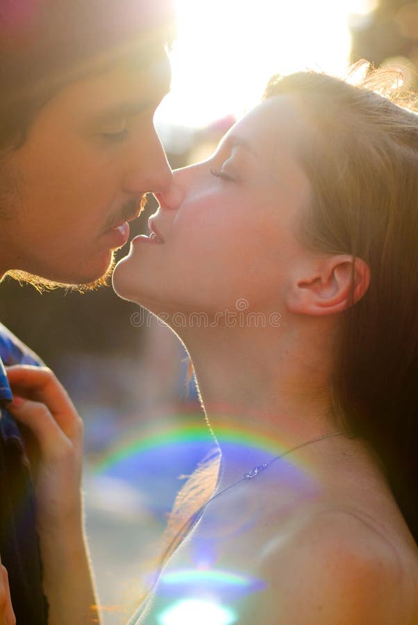 Cute couple man and woman kissing in light flare