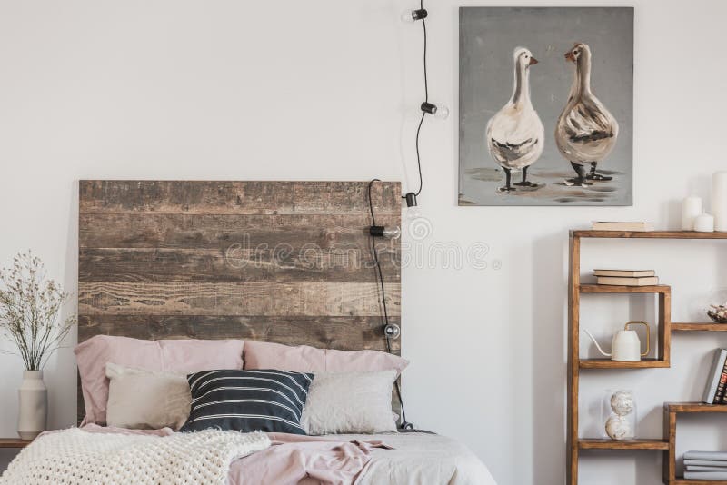 Cute ducks on grey oil painting in white rustic bedroom interior with fancy bookshelf and bed with wooden headboard