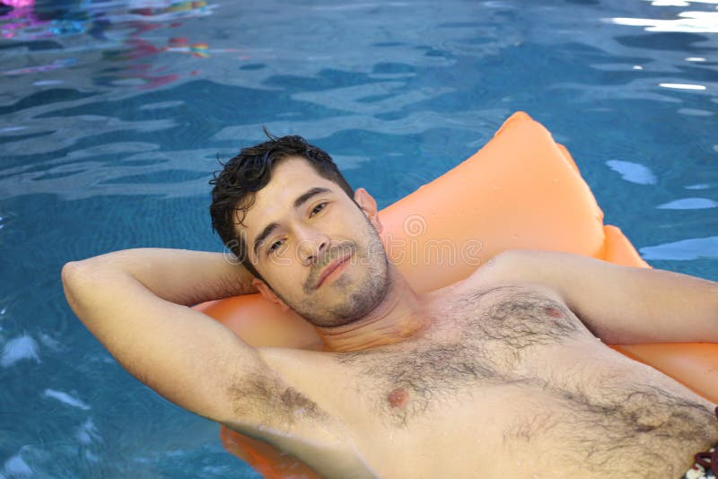 Cute ethnic man sunbathing in swimming pool.