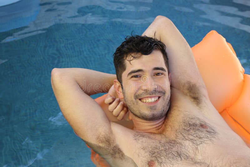 Cute ethnic man sunbathing in swimming pool.