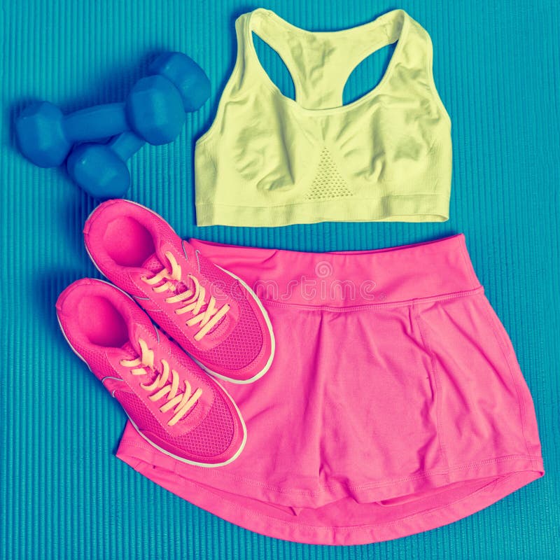 Cute fitness clothing -Sports bra and skort skirt fashion outfit to wear at the gym. Clothes layed on exercise mat with dumbbells royalty free stock image Cute fitness clothing -Sports bra and skort skirt fashion outfit to wear at the gym. Clothes layed on exercise mat with dumbbells royalty free stock image