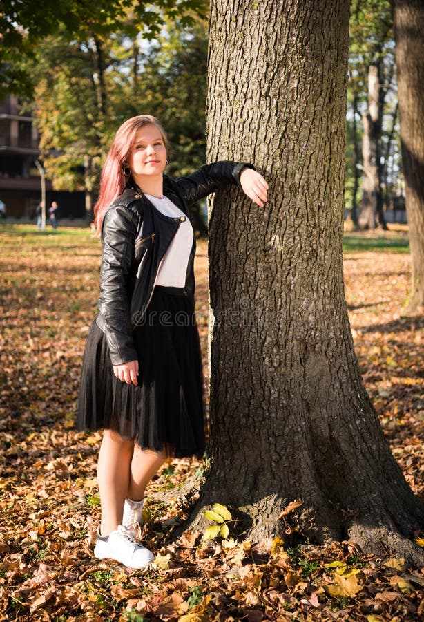 Cute 15-flicka i moderna kläder som står i höstparken i sommar arkivfoton