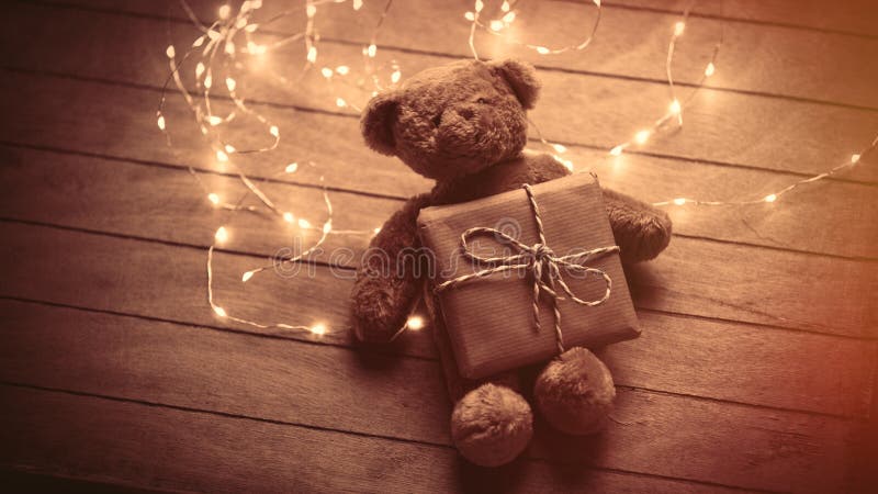 cute fluffy teddy bear with gift and bright garland on the wonderful brown wooden background stock photos cute fluffy teddy bear with gift and bright garland on the wonderful brown wooden background stock photos