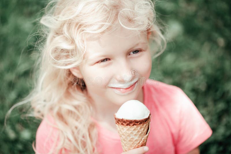 Cute Funny Adorable Girl With Long Messy Blonde Hair Sitting In Park Eating Licking Ice Cream 