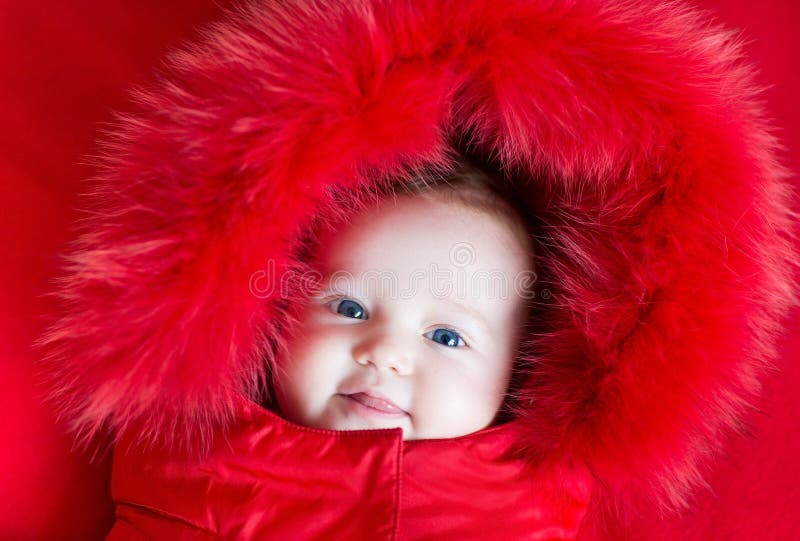 Cute funny baby girl with big blue eyes in warm jacket