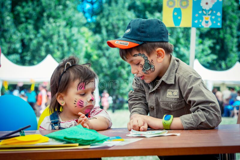 Cute and funny boy and girl with face paintings on Charity Family festival