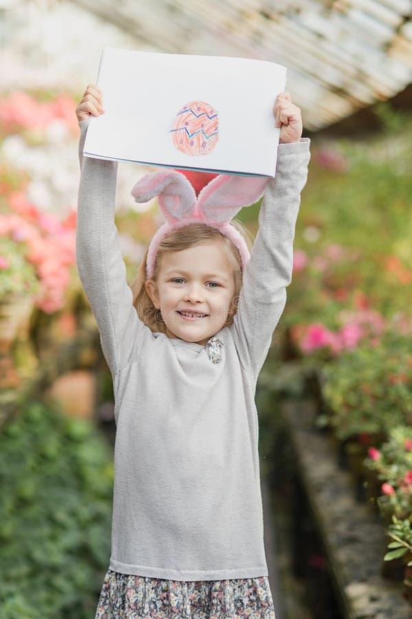 Cute funny girl with Easter bunny ears at garden. easter concept. Laughing child at Easter egg hunt