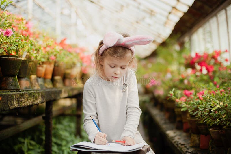 Cute funny girl with Easter bunny ears at garden. easter concept. Laughing child at Easter egg hunt