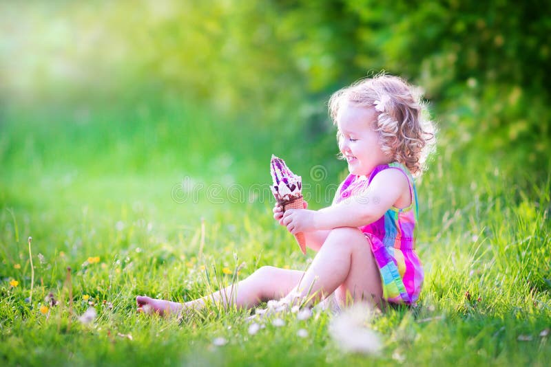 Cute funny girl eating ice cream in sunny garden