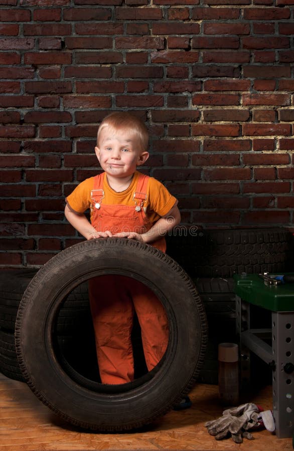 Cute and funny little mechanic with a tire