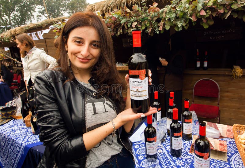 Cute georgian woman showing bottles of red wine, made specialy for festival