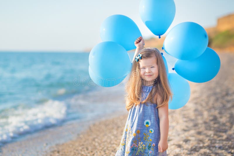 Cute girl with balloons posing on beach of ocean sea coast with sandy rocky land , a holiday, a sea trip royalty free stock photos Cute girl with balloons posing on beach of ocean sea coast with sandy rocky land , a holiday, a sea trip royalty free stock photos